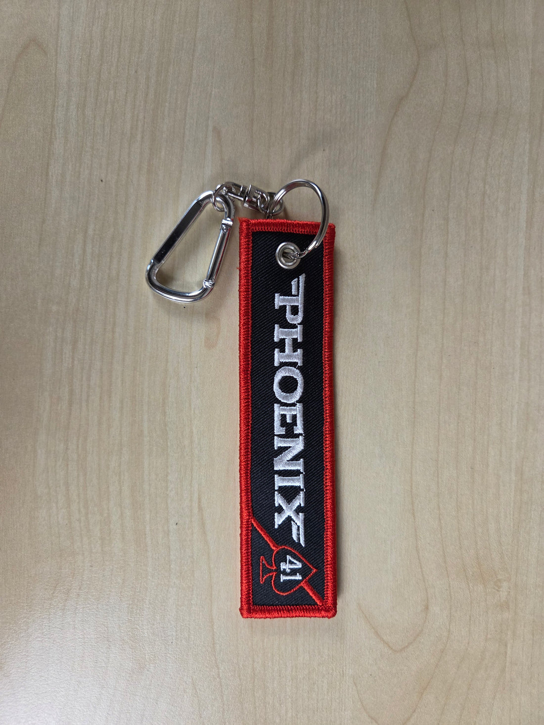 Keychain with 'PHOENIX 41' logo on a wooden surface