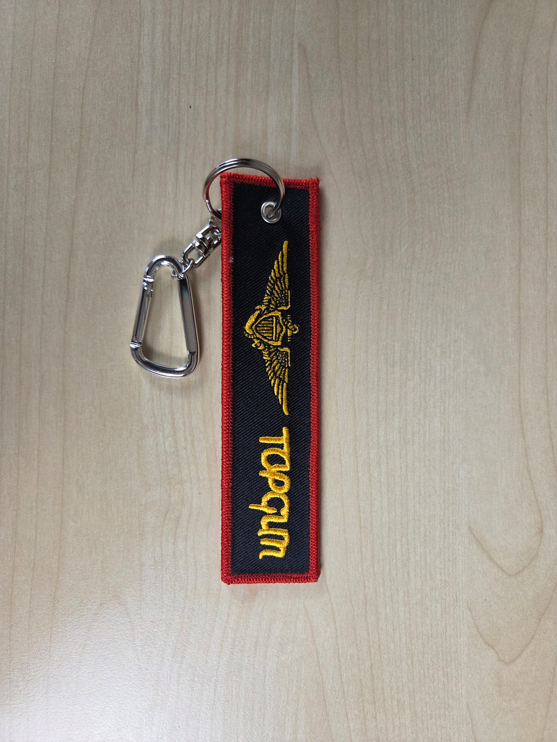 Top Gun keychain with red and yellow design on a wooden surface