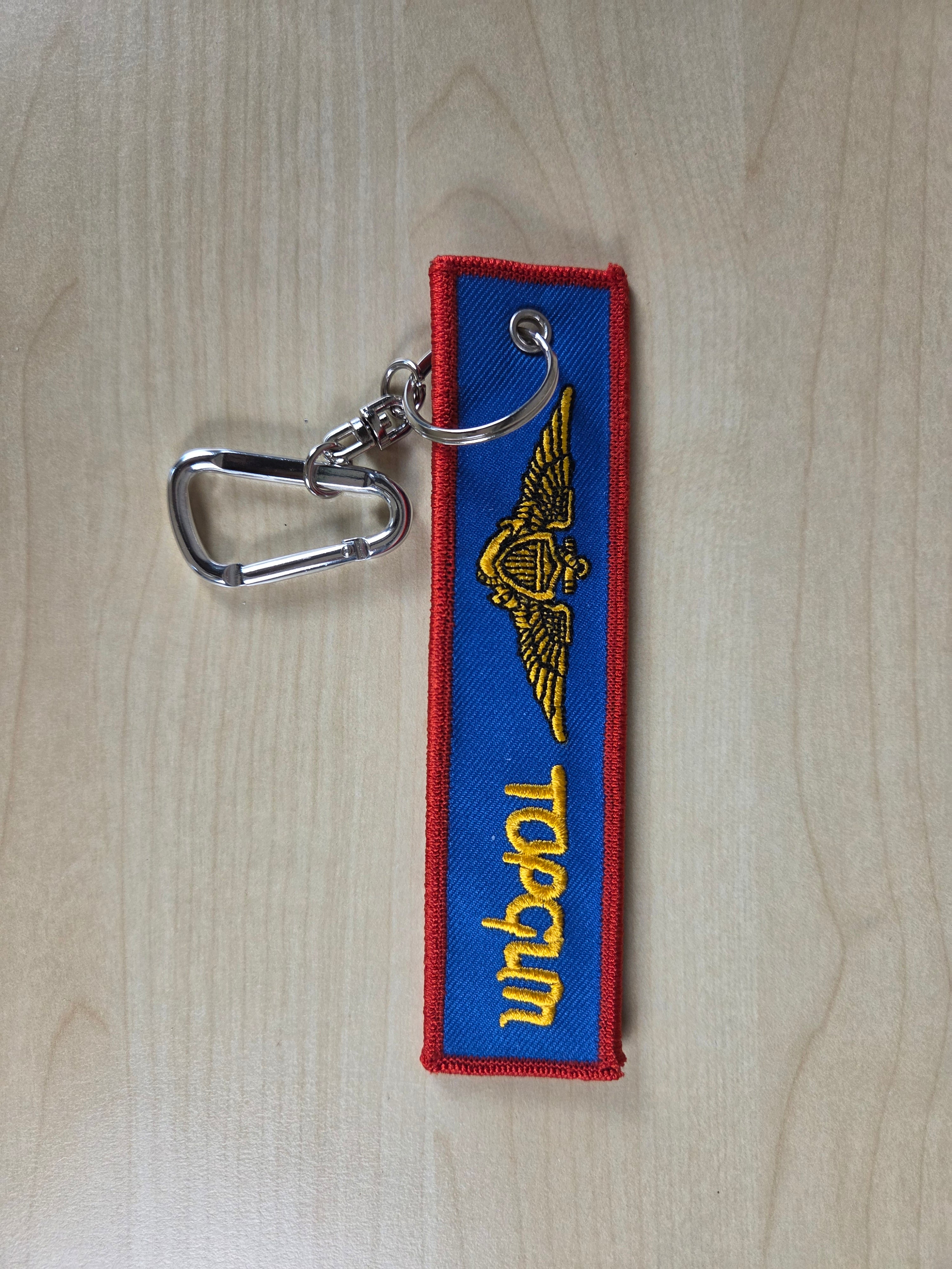 Keychain with 'Topgun' logo on a wooden surface