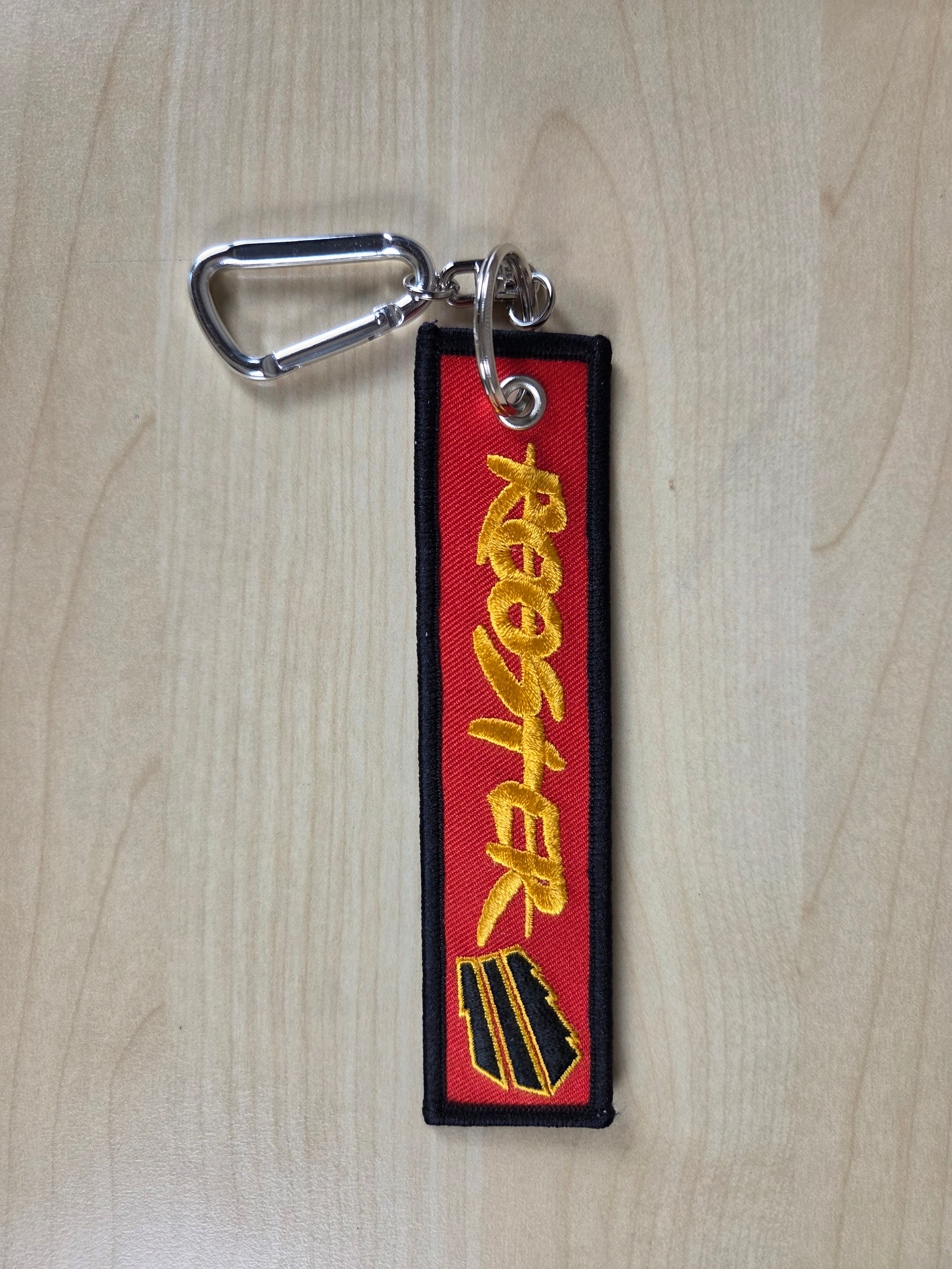 Keychain with 'ROOSTER' branding on a wooden surface