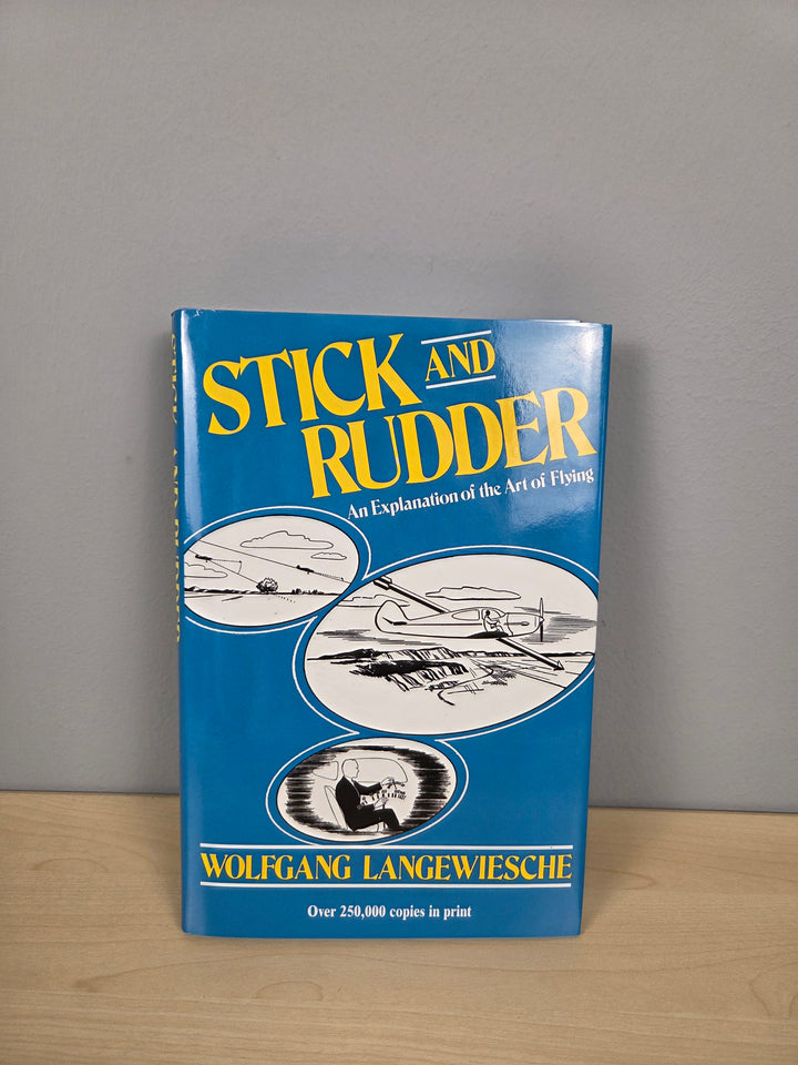 A vintage hardcover book titled 'Stick and Rudder: An Explanation of the Art of Flying' by Wolfgang Langewiesche, standing upright on a light wood surface against a gray wall.