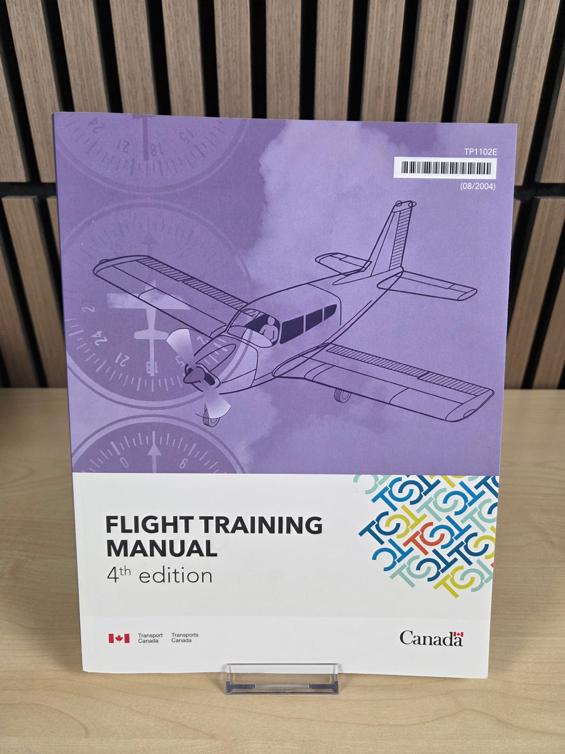 A book named "Flight training manual" sitting on wooden surface.