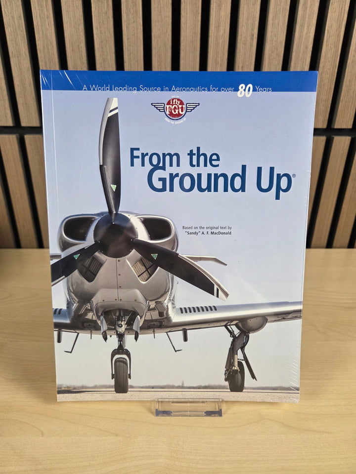 Book titled 'From the Ground Up' with airplane propellers on a wooden surface
