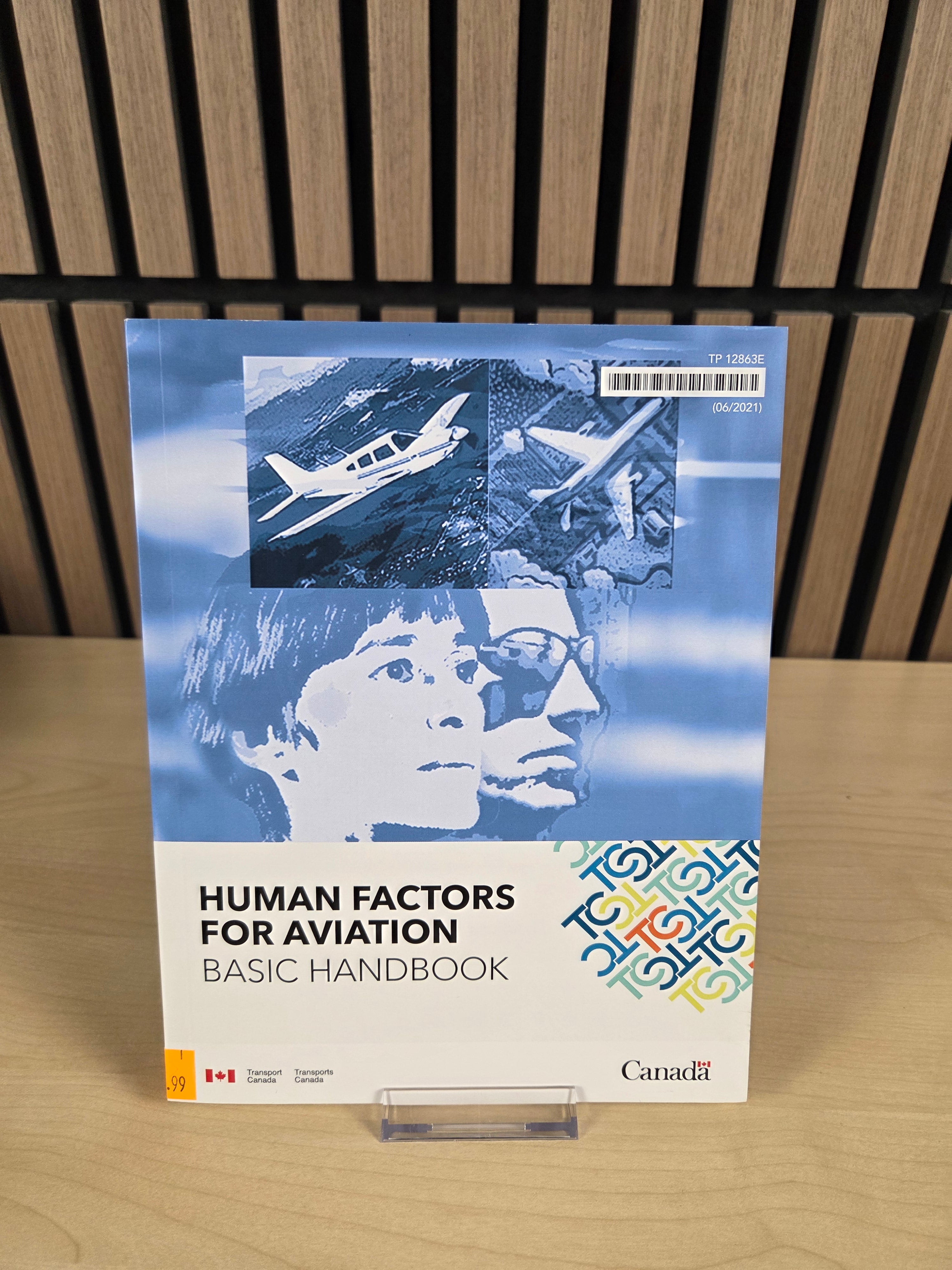Book titled 'Human Factors for Aviation Basic Handbook' on a wooden surface with a slatted background