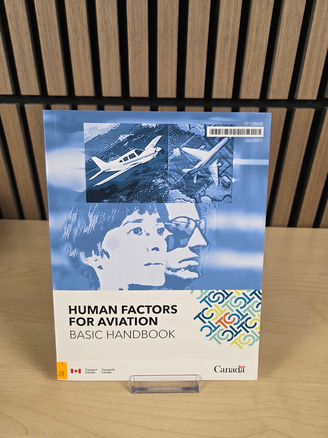 Book titled 'Human Factors for Aviation Basic Handbook' on a wooden surface with a slatted background