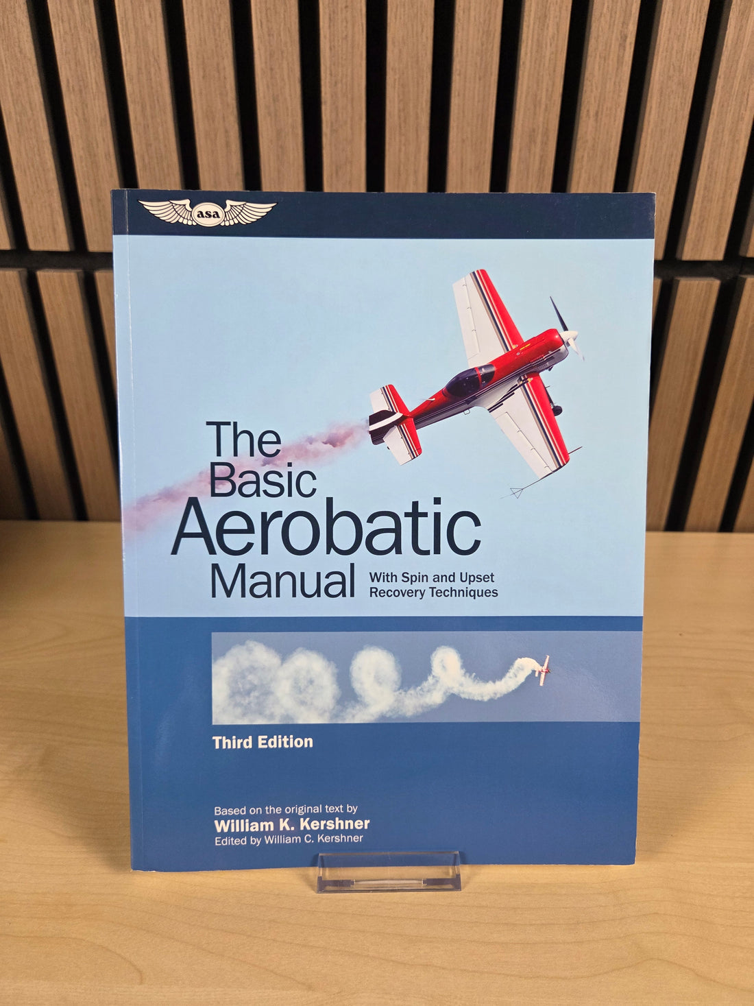 A book named "The basic aerobatic manual" sitting on wood surface