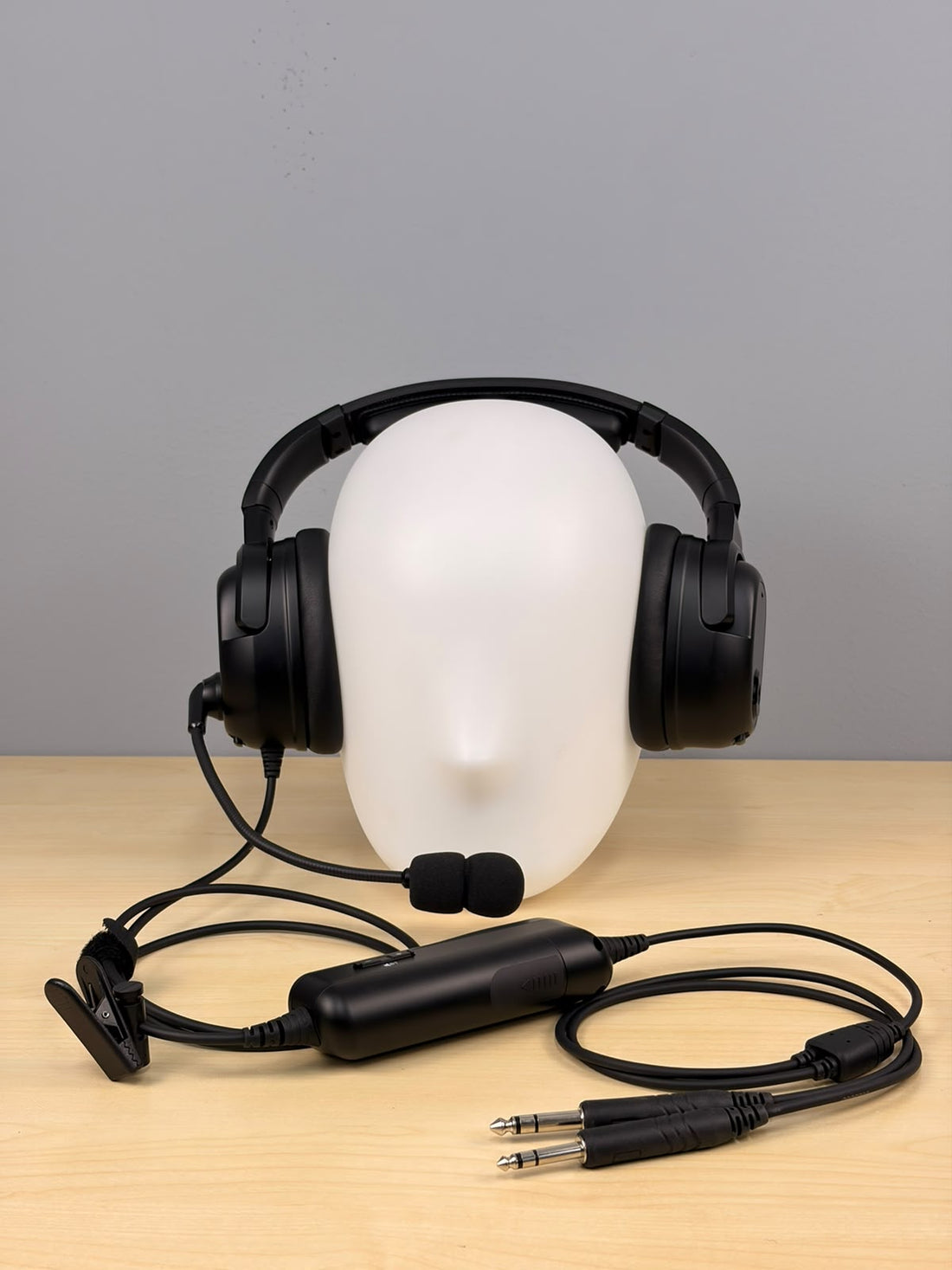 Frontal shot of Raytalk ph700A headset sitting on a fake head and on a wooden desk with gray background 