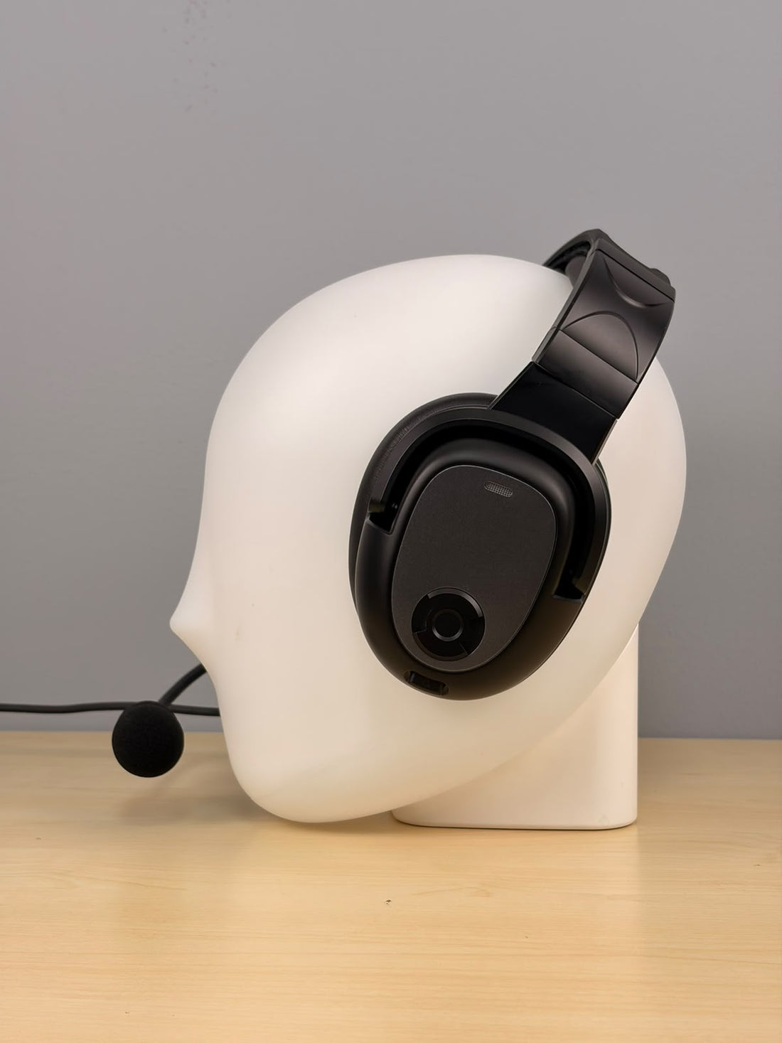 Raytalk ph700A headset sitting on a fake head and on a wooden desk with gray background 
