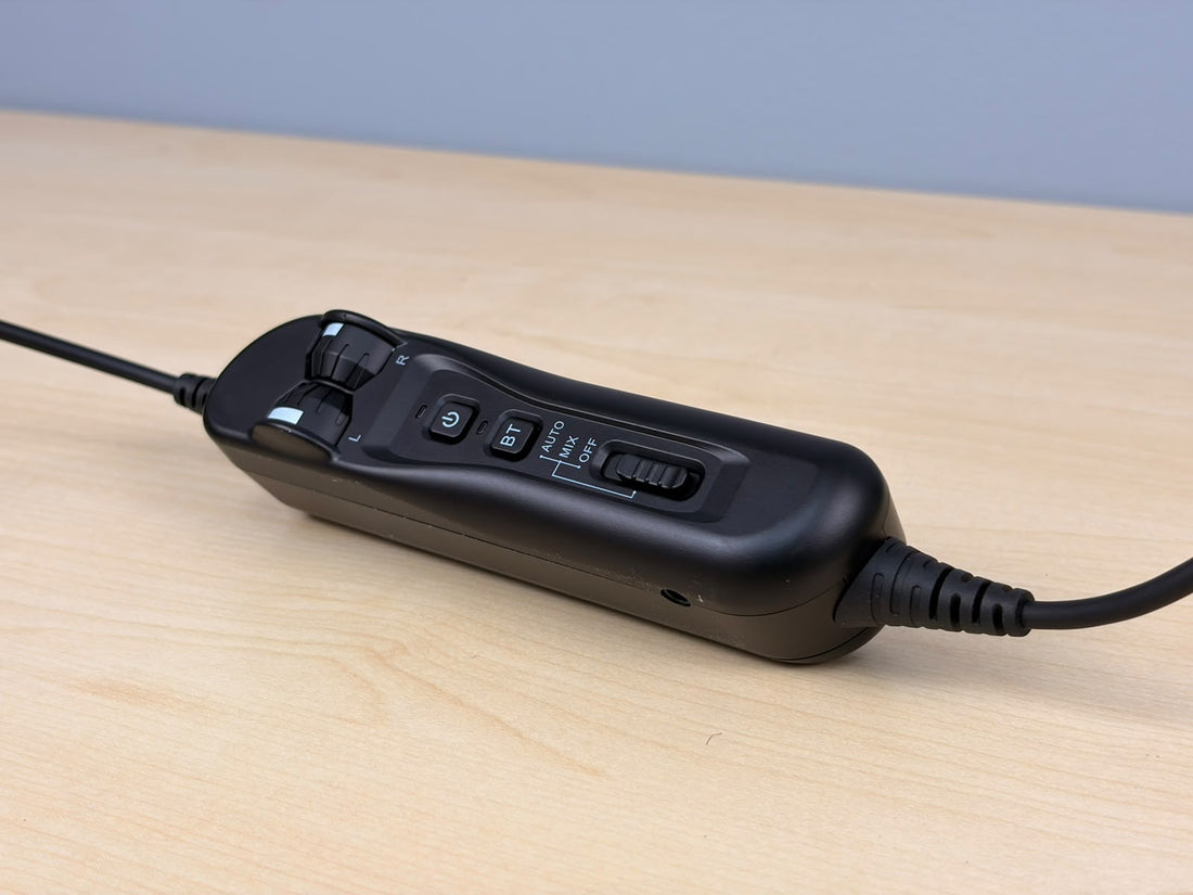 The controller of Raytalk ph700A headset sitting on a wooden desk with gray background 
