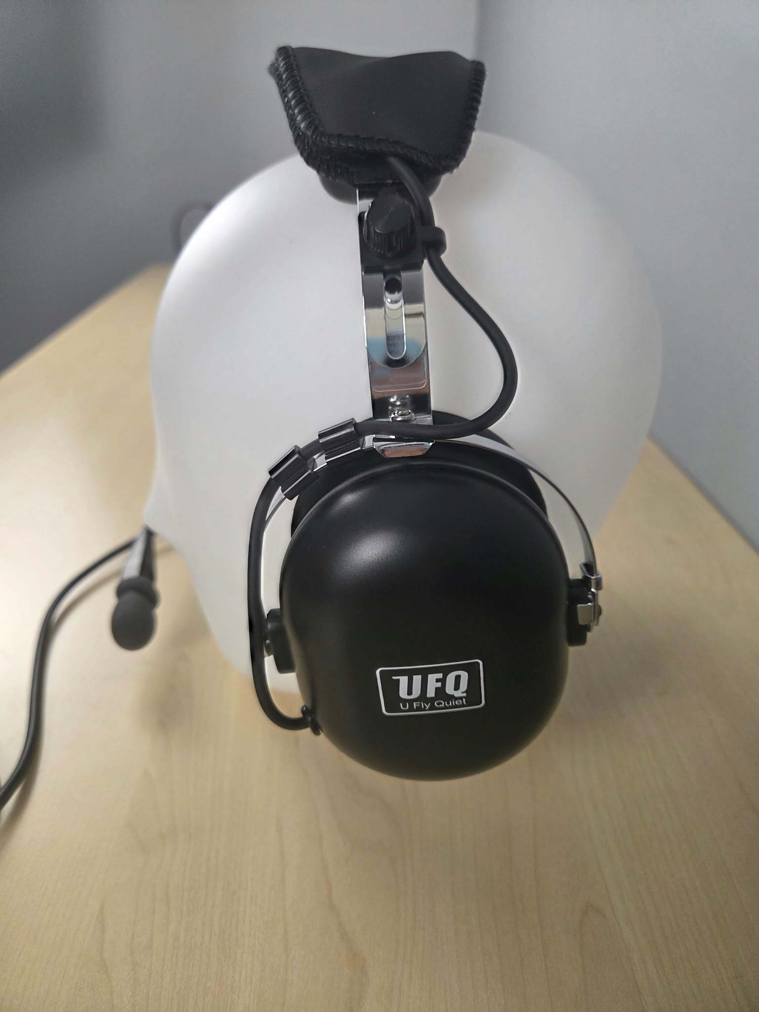 Side view of UFQ P1 headset sitting on a wooden desk with gray background