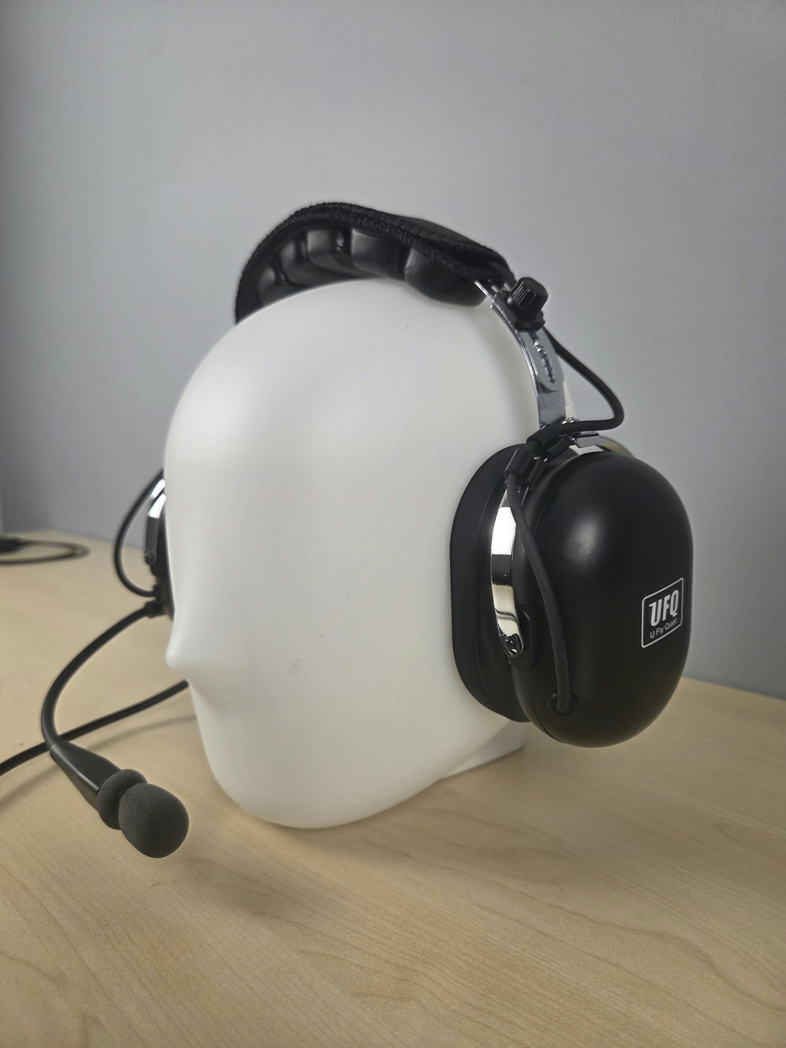 Close up of UFQ P1 headset sitting on a wooden desk with gray background