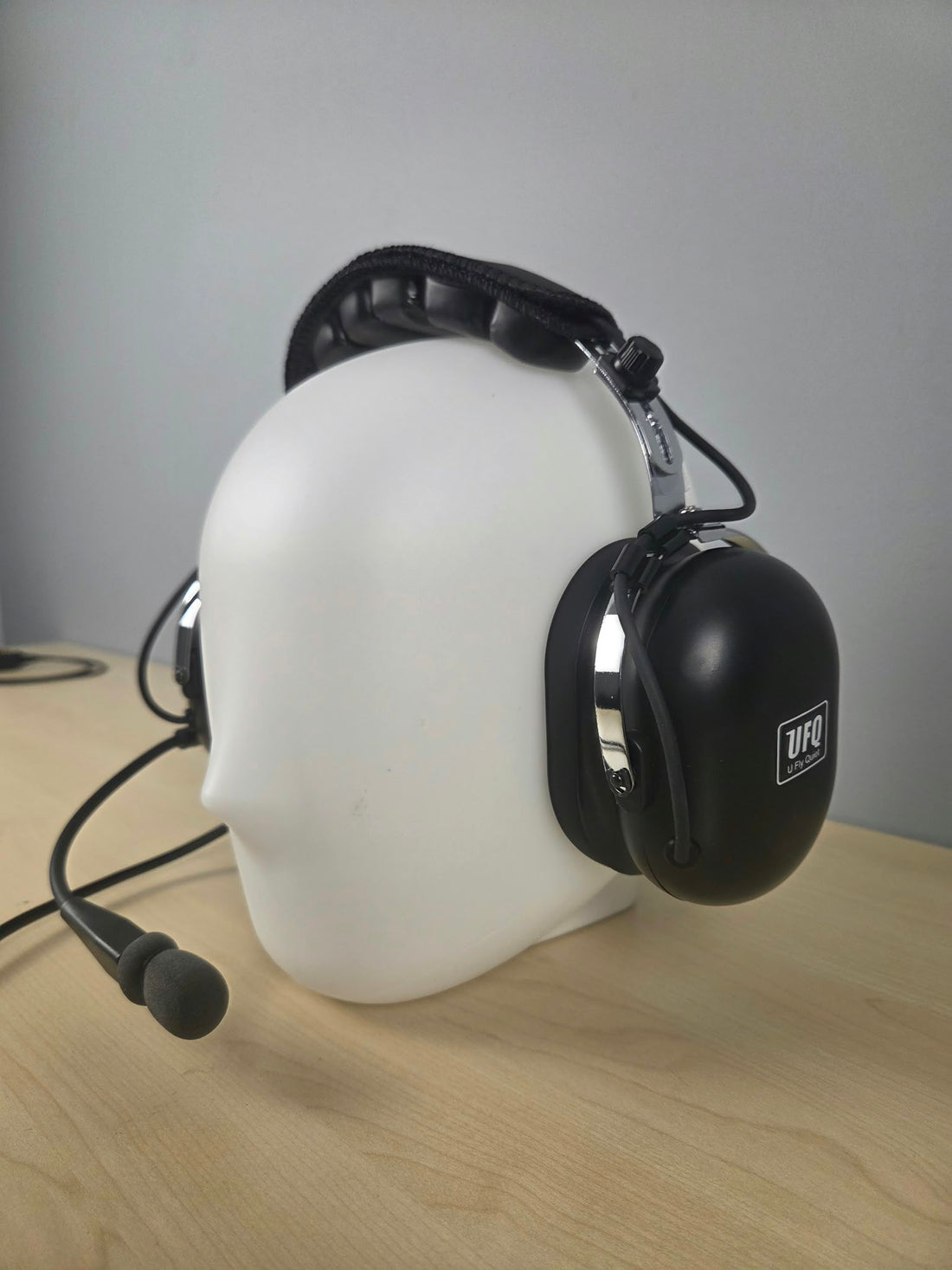 Close up of UFQ P1 headset sitting on a wooden desk with gray background
