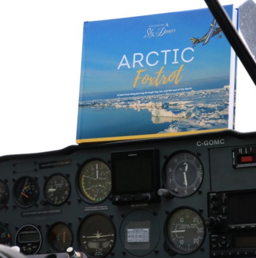 Book titled 'Arctic Fox Trot' on a cockpit dashboard with instruments